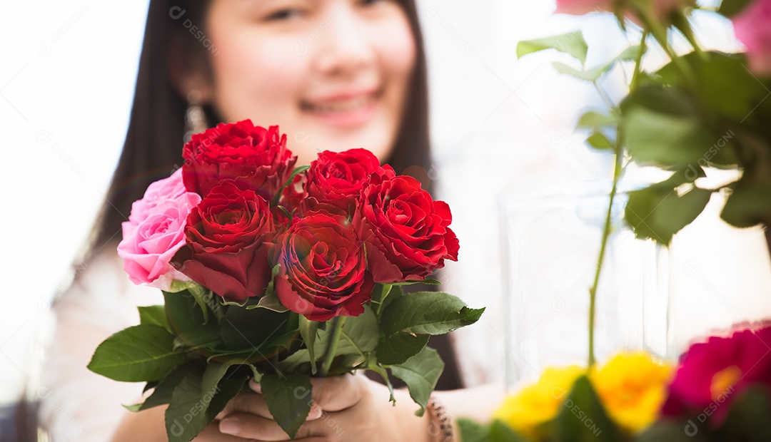 Mulher se preparando para aparar rosas vermelhas e cor de rosa e lindos arranjos de flores em casa