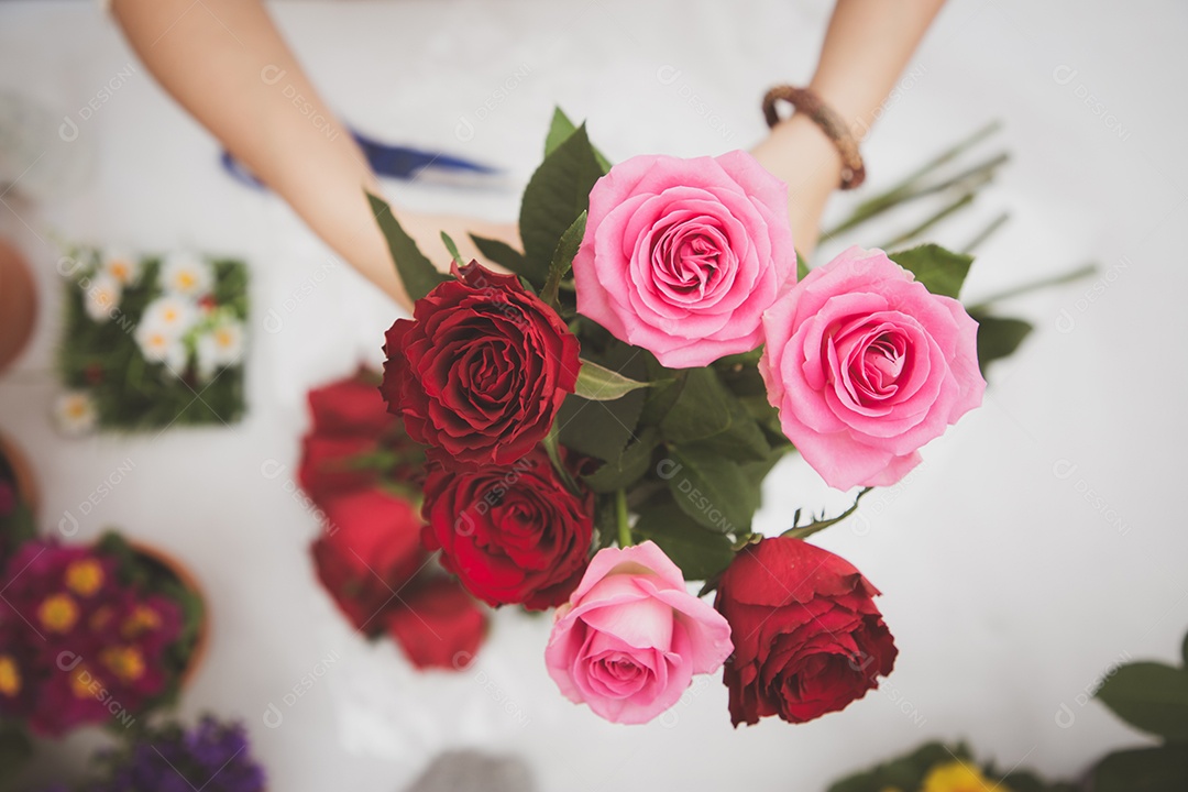 Mulher se preparando para aparar rosas vermelhas e cor de rosa e lindos arranjos de flores em casa