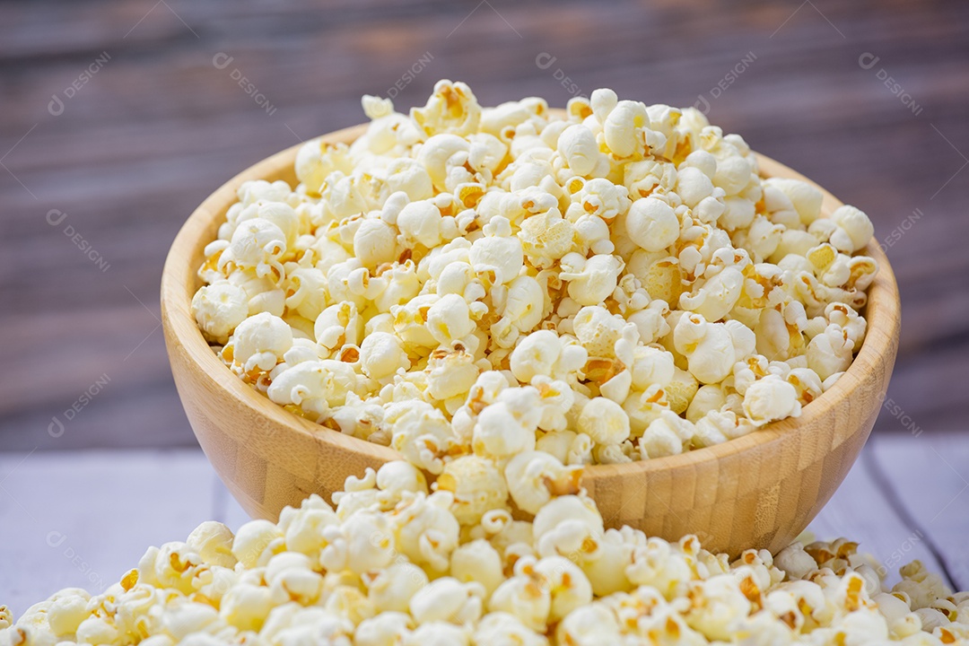 Pipoca de manteiga assada na tigela grande de madeira sobre a mesa de madeira