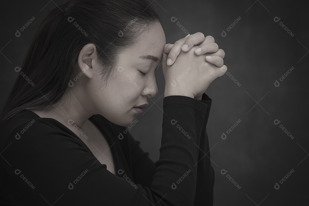 Rosto asiático mulher orando e adorando a Deus usando as mãos para orar em crenças religiosas e adoração cristã na igreja ou em locais gerais em fundo branco e preto