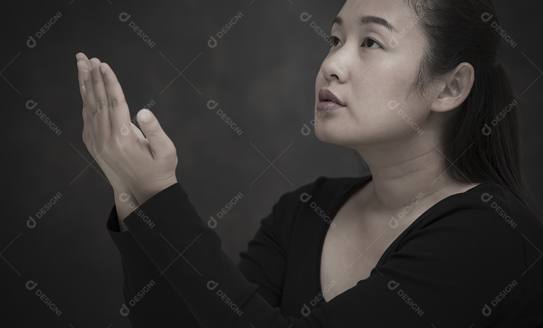 Rosto asiático mulher orando e adorando a Deus usando as mãos para orar em crenças religiosas e adoração cristã na igreja ou em locais gerais em fundo branco e preto