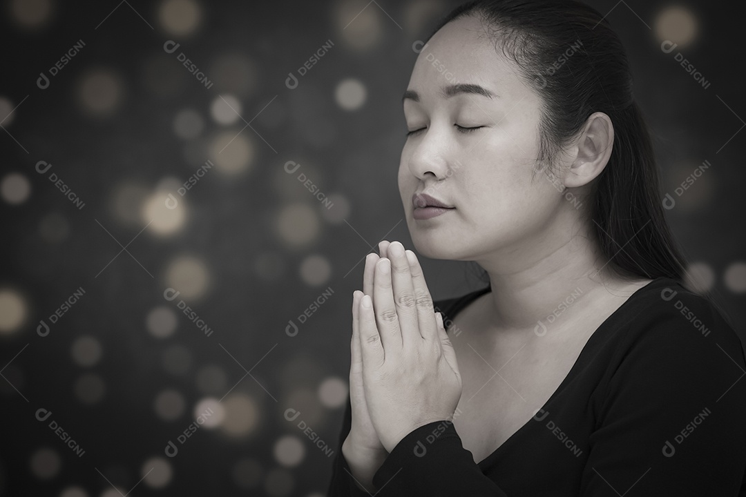 Rosto asiático mulher orando e adorando a Deus usando as mãos para orar em crenças religiosas e adoração cristã na igreja ou em locais gerais em fundo branco e preto