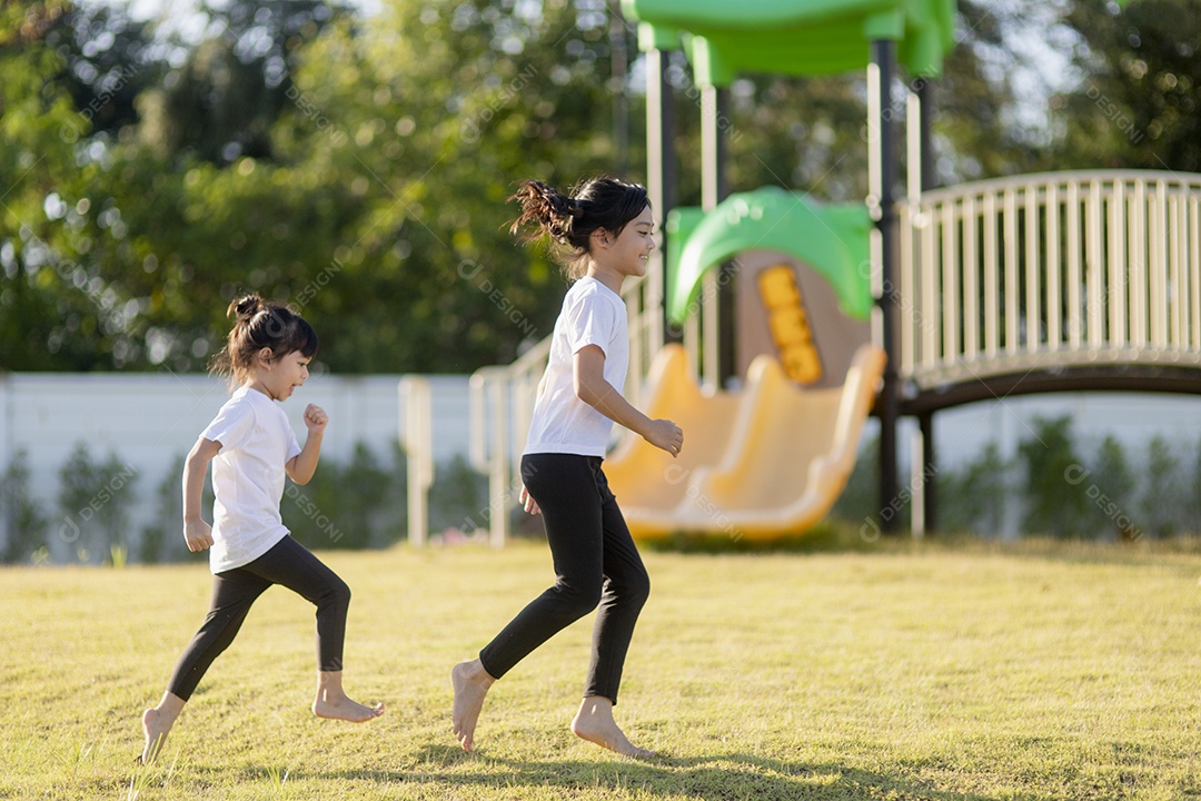 Duas meninas asiáticas se divertindo em um playground ao ar livre no verão
