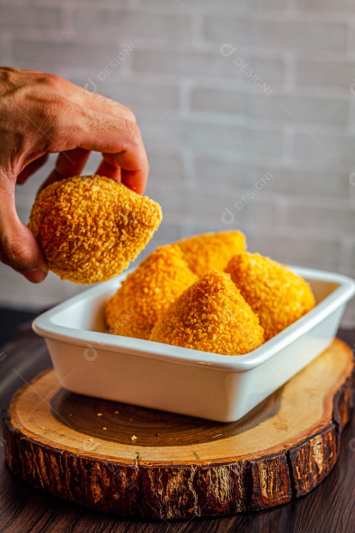 Imagem de homem segurando coxinhas.