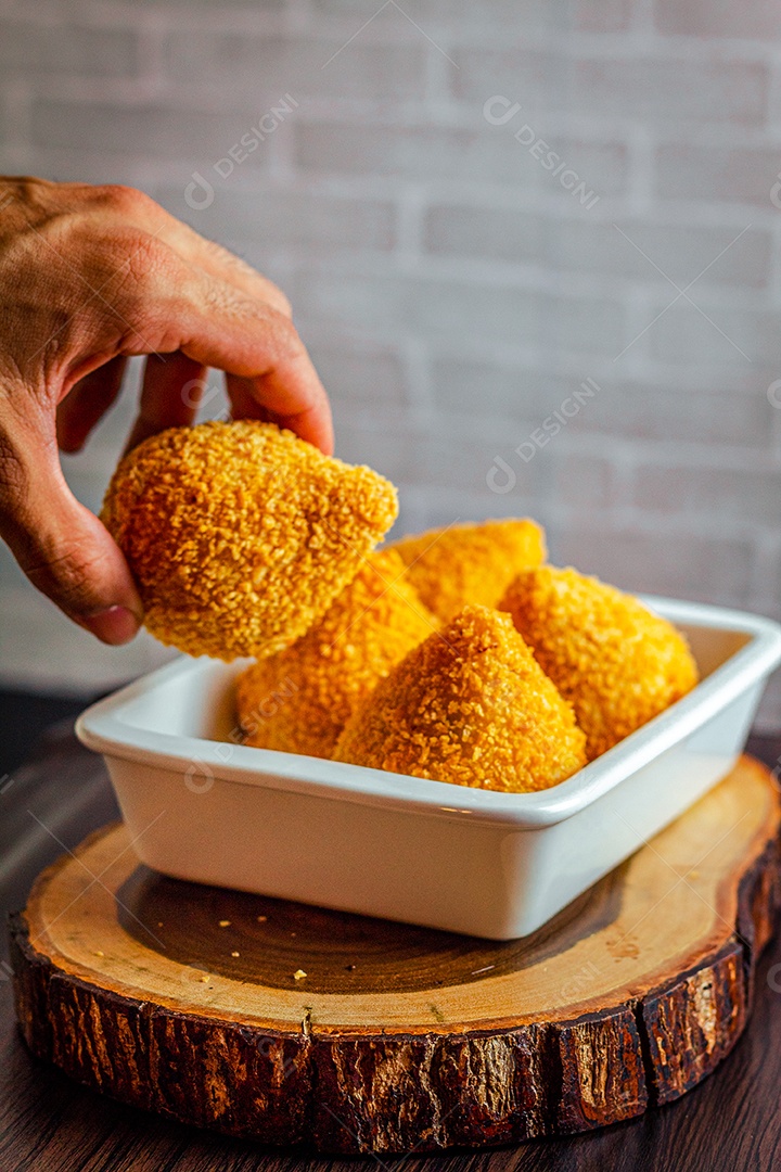Imagem de jovem segurando coxinhas.