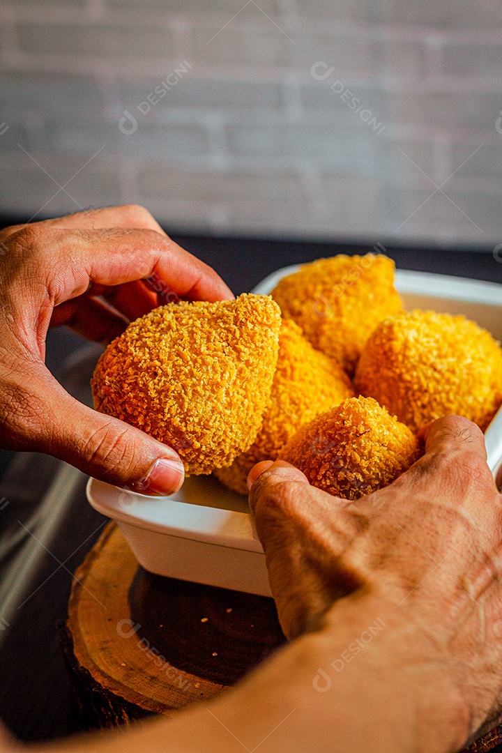 Imagem de homem segurando coxinhas.