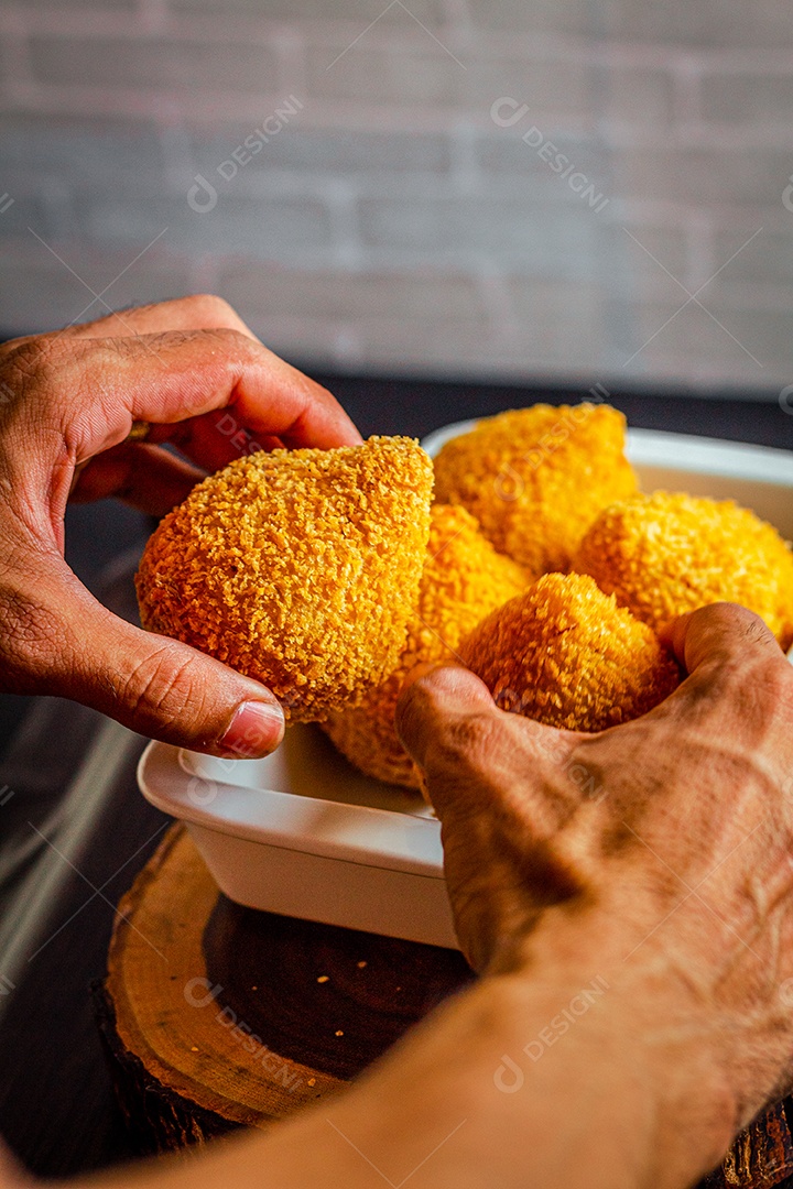 Imagem de homem segurando coxinhas.