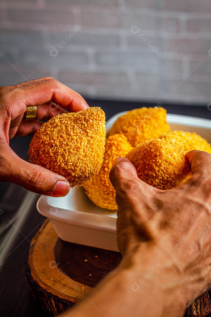 Imagem de homem segurando coxinhas.