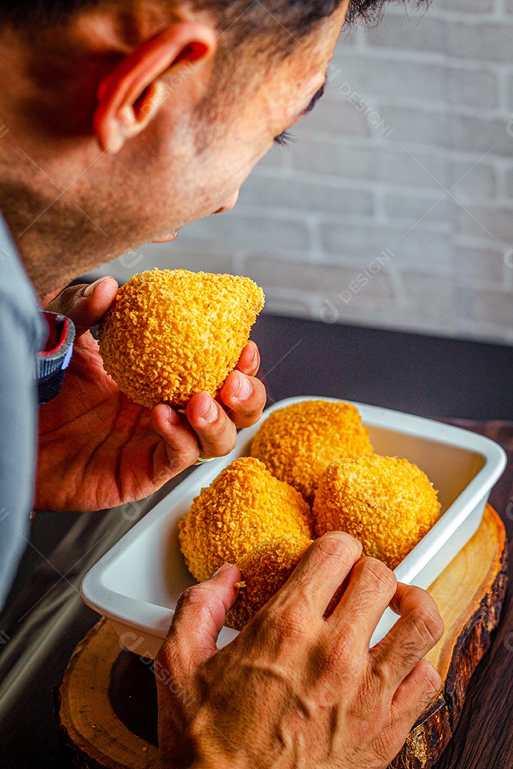 Imagem de homem comendo coxinha.