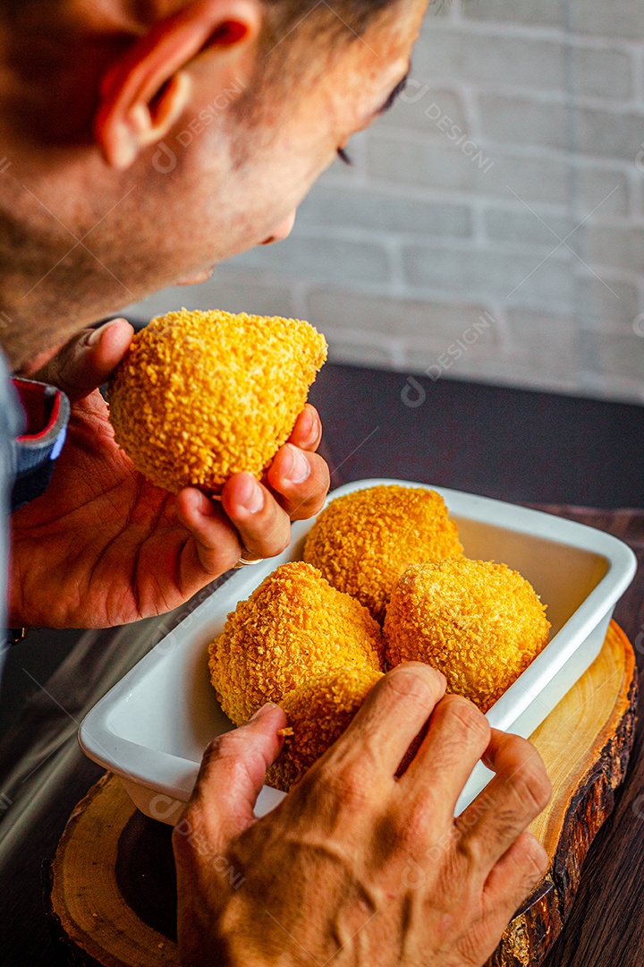 Imagem de homem comendo coxinha.