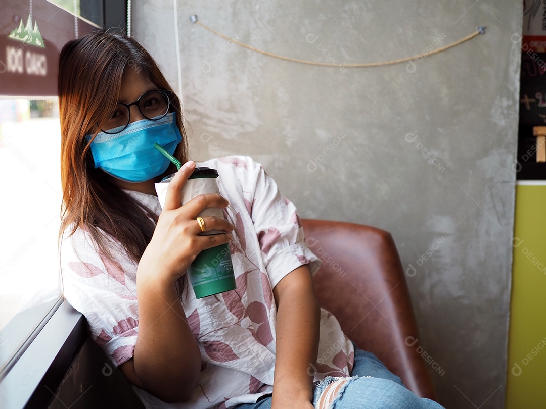 Mulher com máscara protetora facial olhando para a câmera no café.