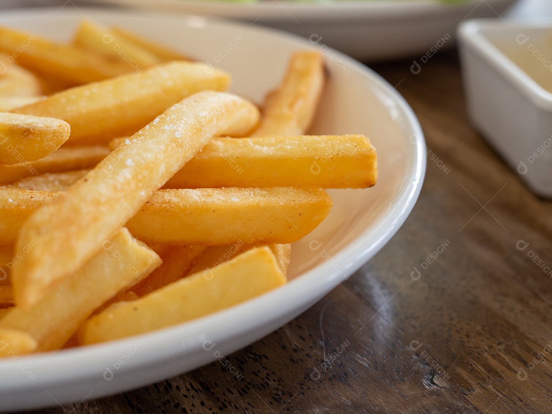 Batatas fritas estão em um prato branco.