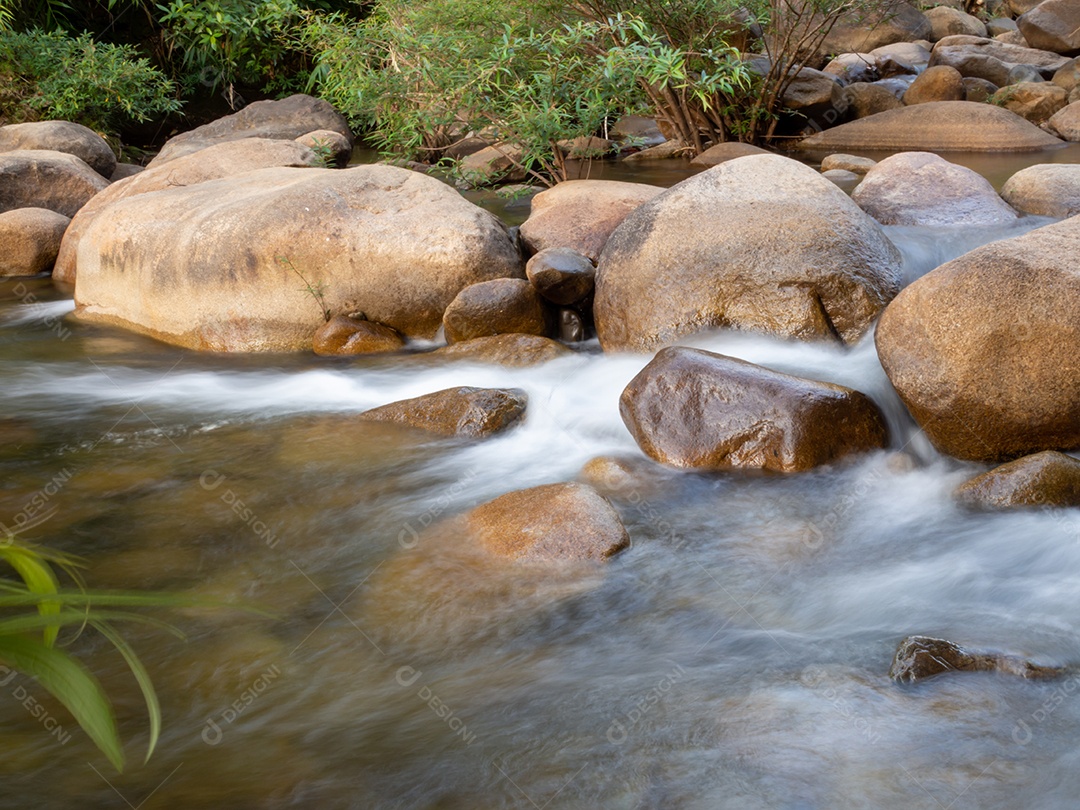Um tiro de longa exposição de um pequeno riacho fluindo através de um marrom.