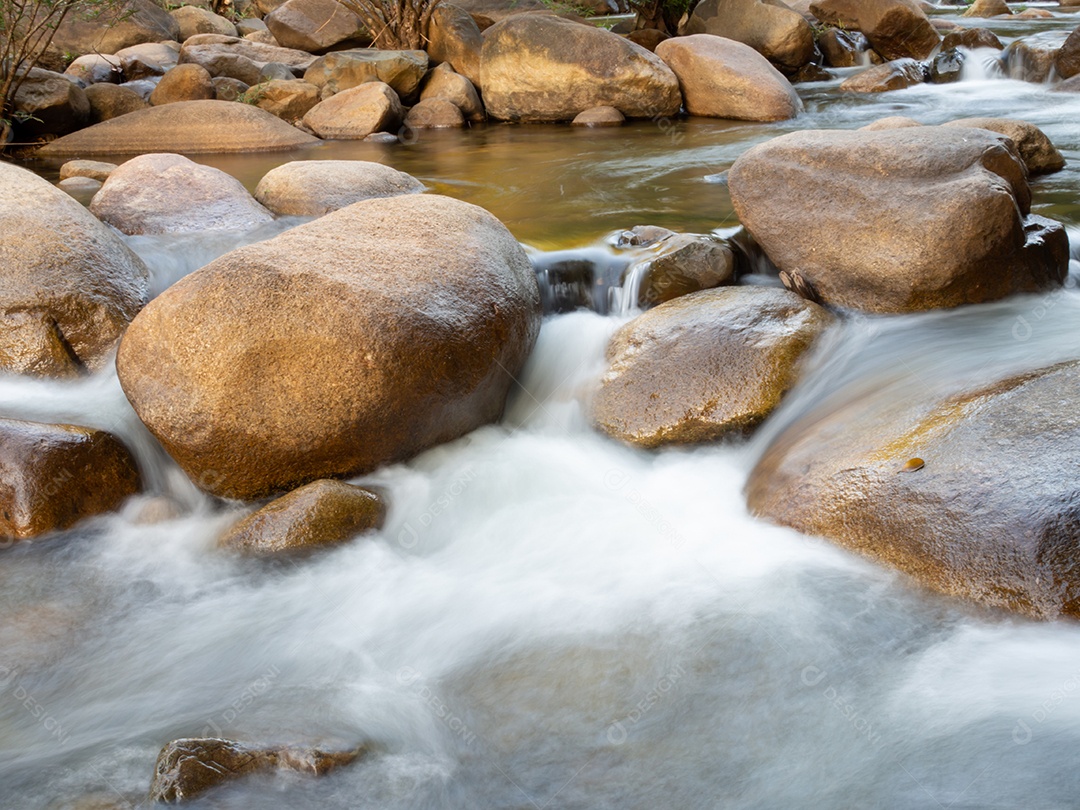 Um tiro de longa exposição de um pequeno riacho fluindo através de um marrom.
