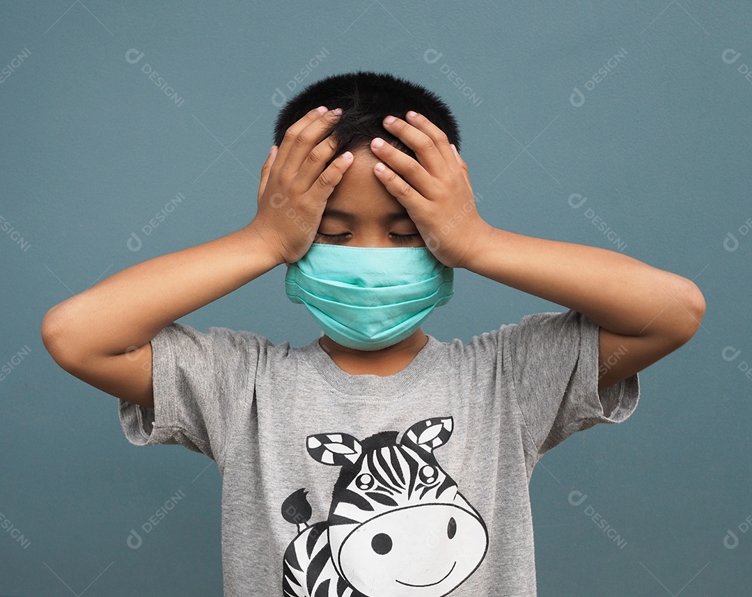 Um menino usando uma máscara protetora e segurando a mão na cabeça.