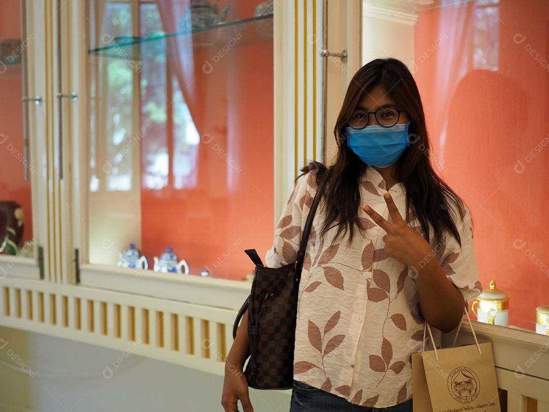 Mulher com máscara protetora facial olhando para a câmera no shopping.