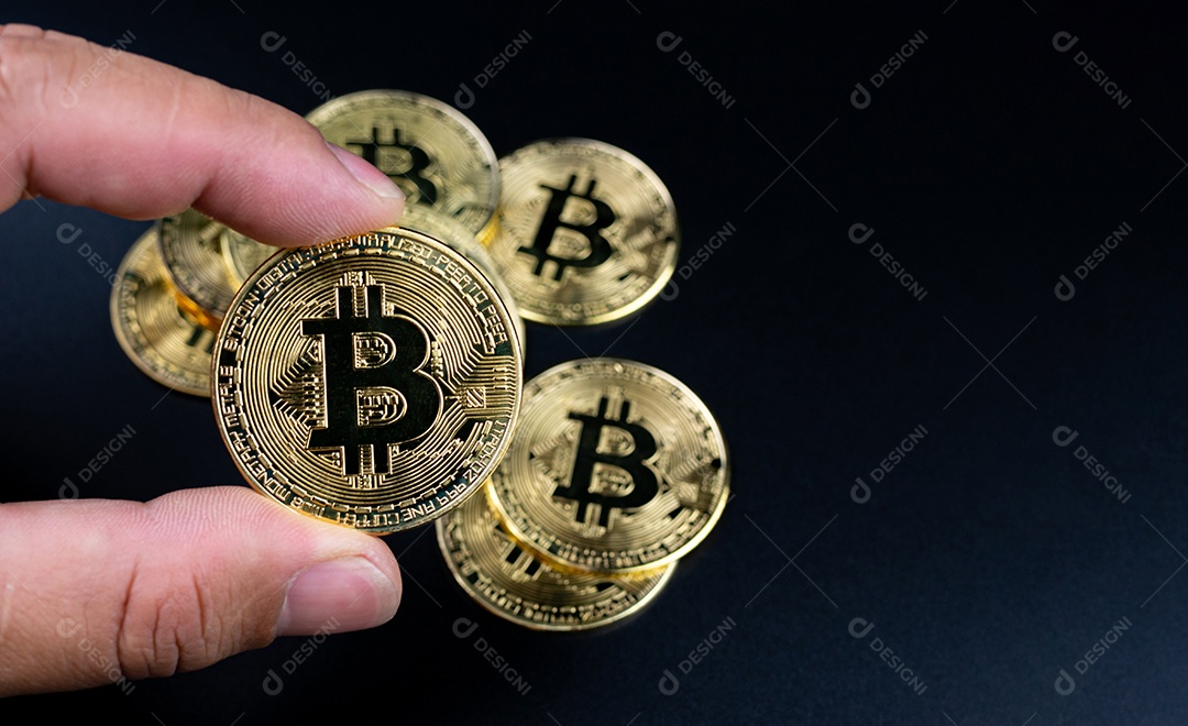 Dedos humanos segurando bitcoins em um fundo preto.