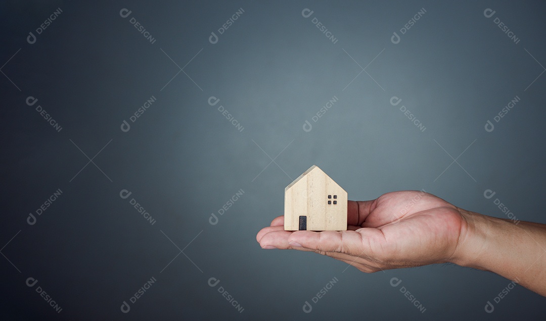 Conceito de venda de uma casa. Uma mão está segurando uma casa modelo.