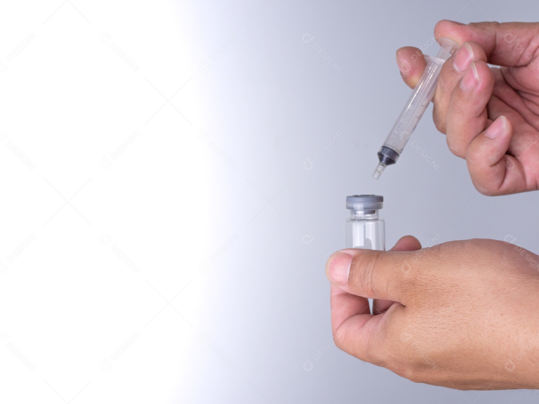 A mão de um homem está segurando um frasco de vacina e um estilingue para injetar.