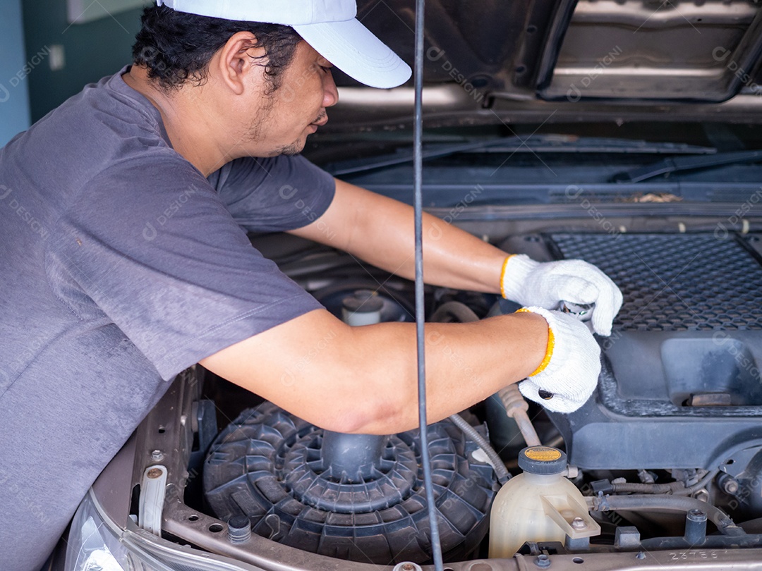 Mecânico segurando uma chave de bloco enquanto conserta um carro.