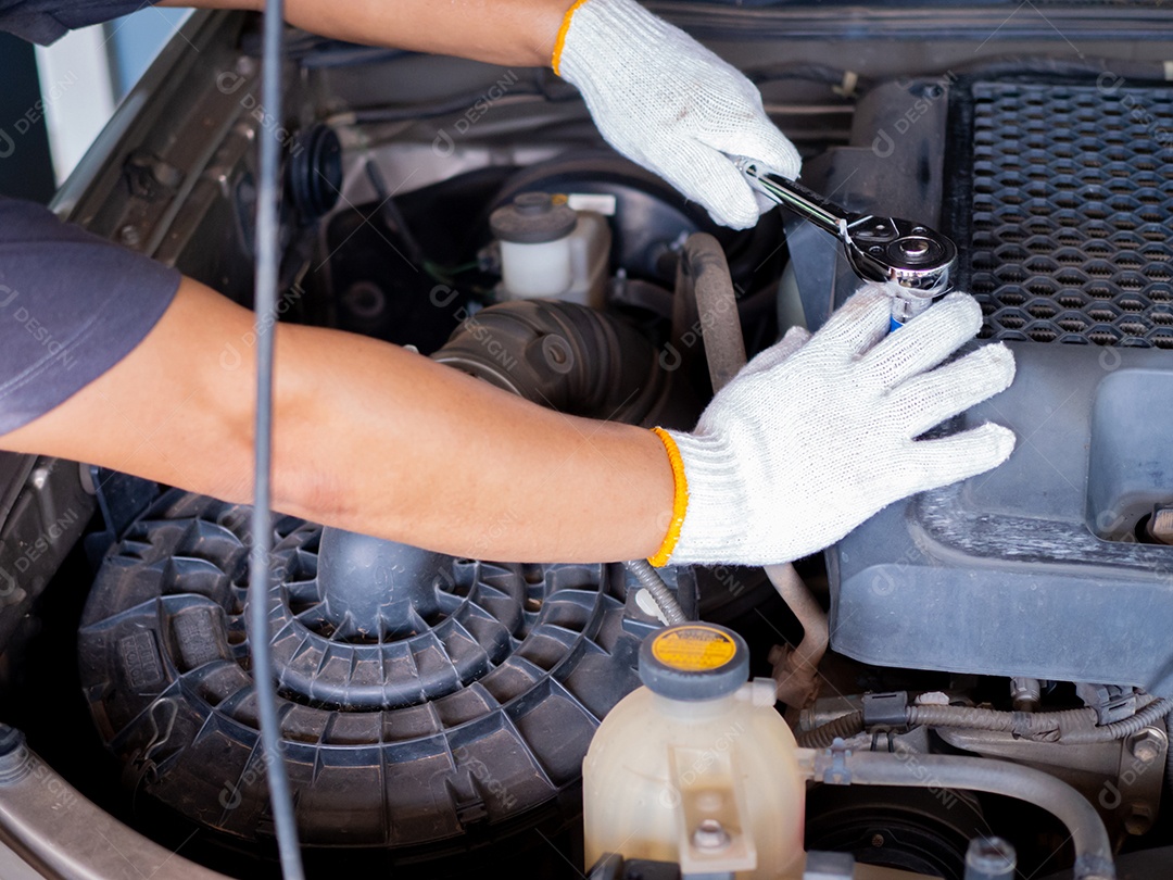 Mecânico segurando uma chave de bloco enquanto conserta um carro.