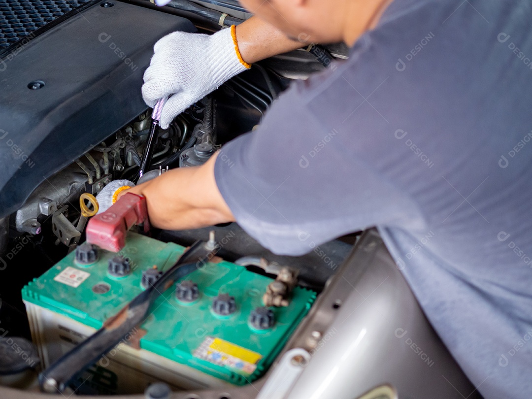 Mecânico segurando uma chave de bloco enquanto conserta um carro.