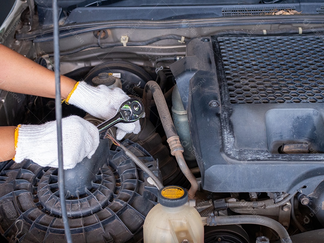 Mecânico segurando uma chave de bloco enquanto conserta um carro.