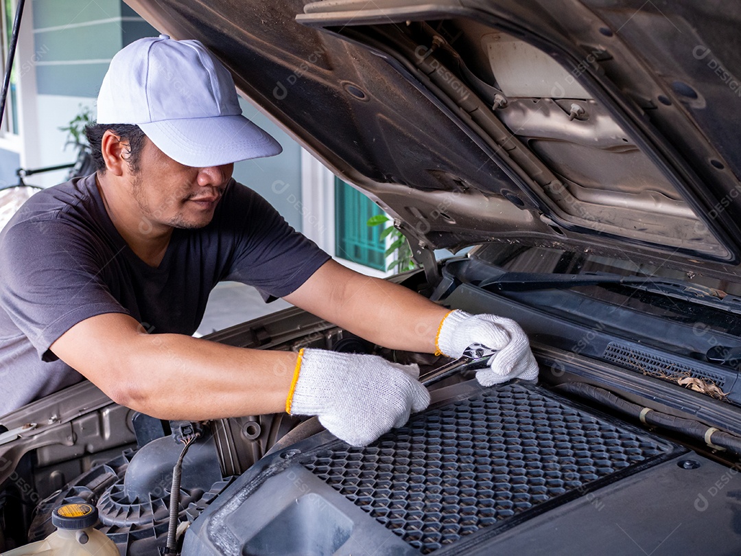 Mecânico segurando uma chave de bloco enquanto conserta um carro.