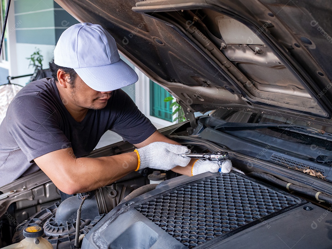 Mecânico segurando uma chave de bloco enquanto conserta um carro.