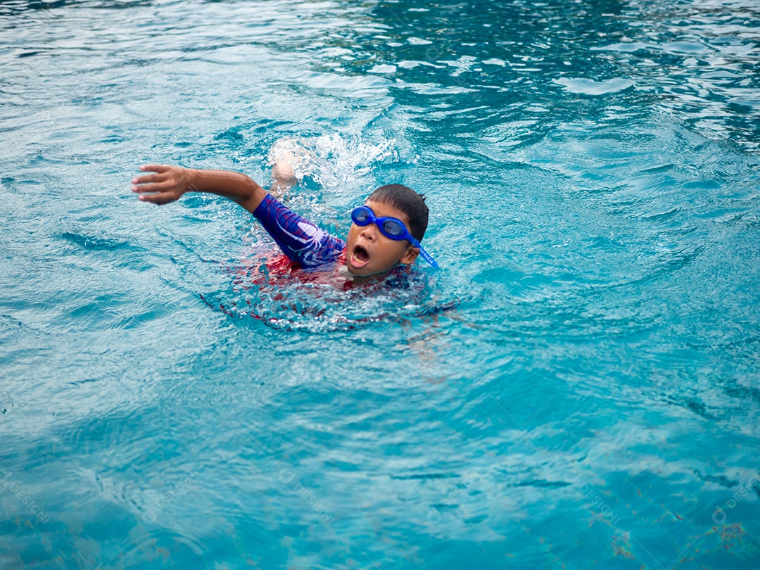 Menino vestindo um maiô e óculos nadando no meio da piscina.