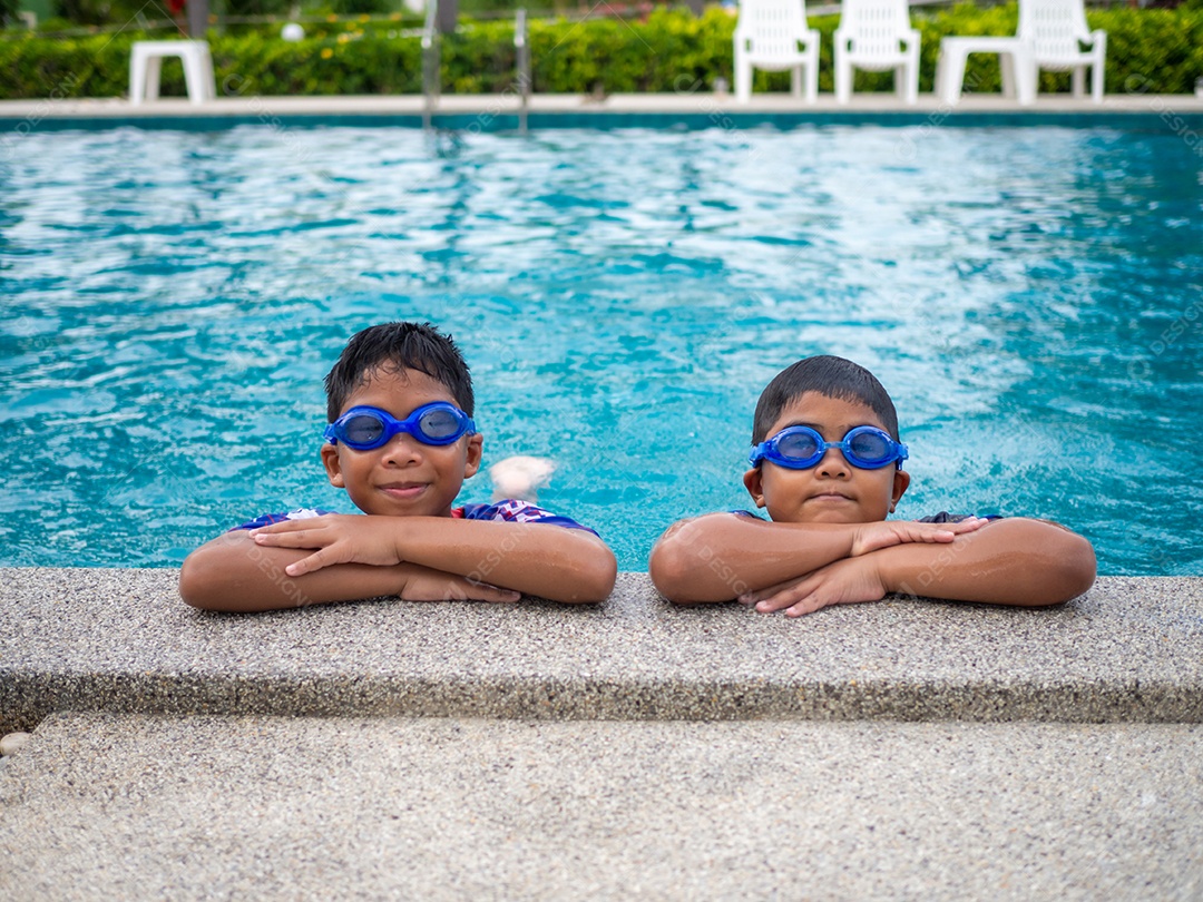 Irmãos de maiô e óculos sorriam empoleirados na beira da piscina.