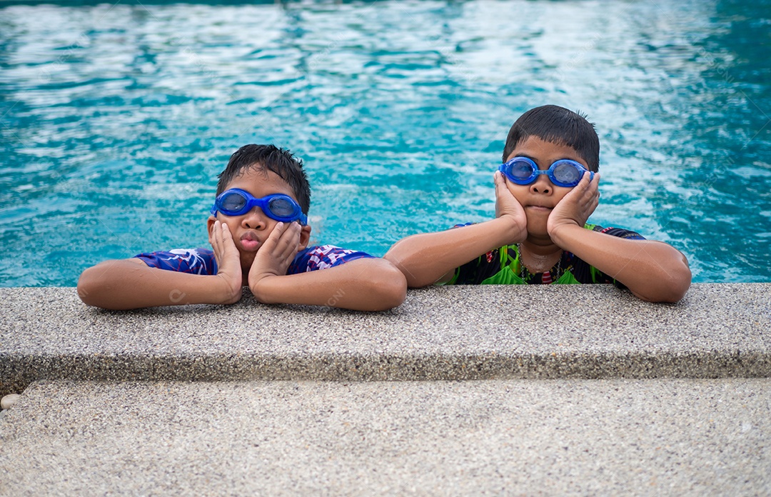 Irmãos de maiô e óculos sorriam empoleirados na beira da piscina.
