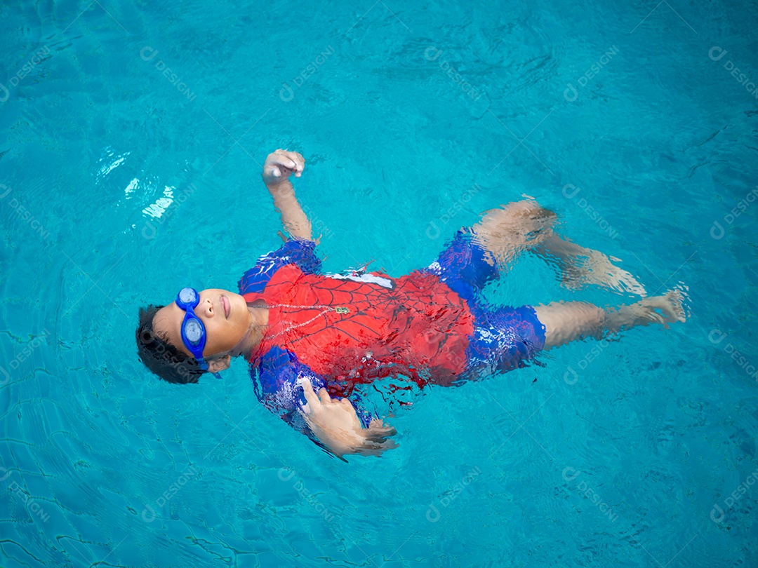Menino vestindo um maiô e óculos nadando no meio da piscina.