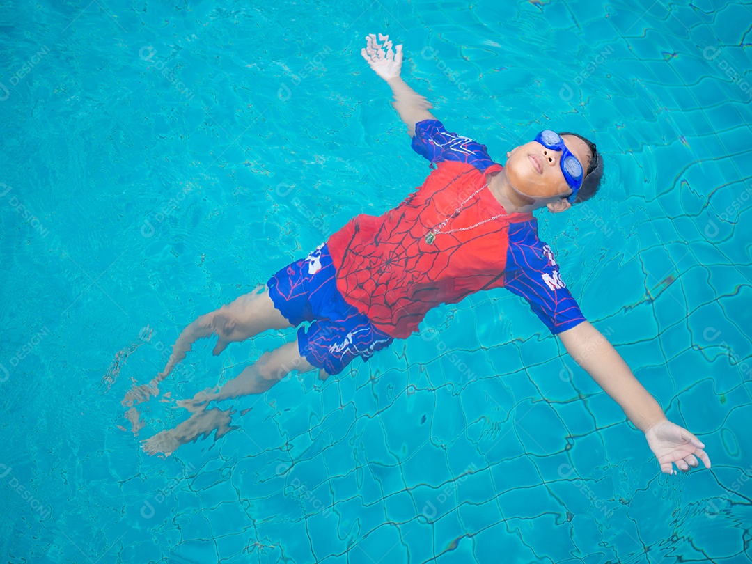 Menino vestindo um maiô e óculos nadando no meio da piscina.