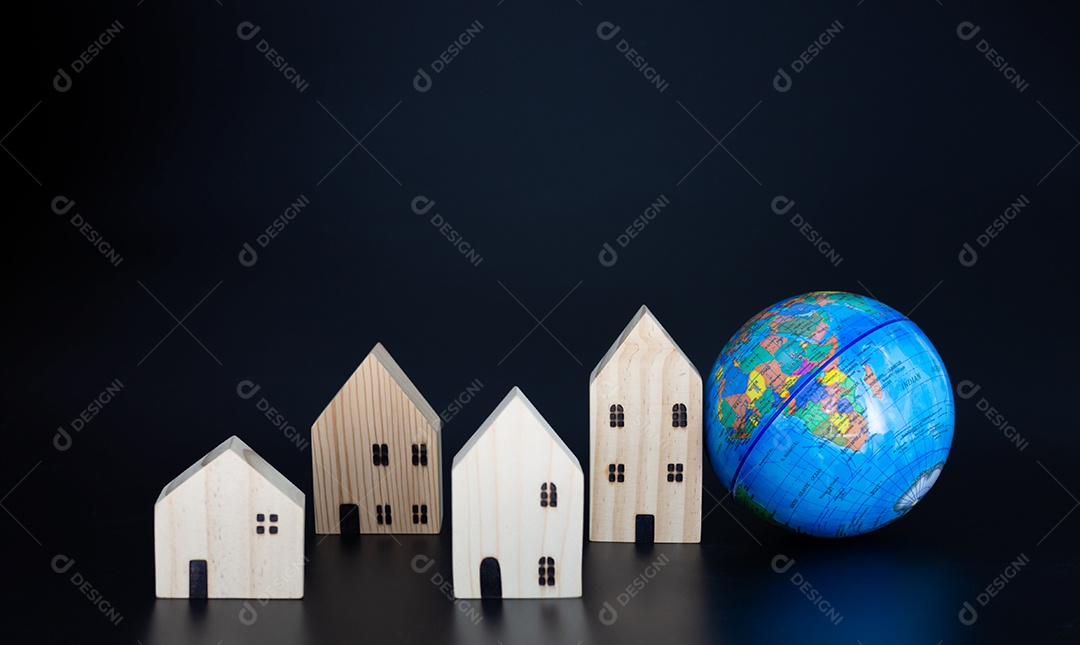 Modele casas de madeira e globos em miniatura em branco sobre um fundo preto.