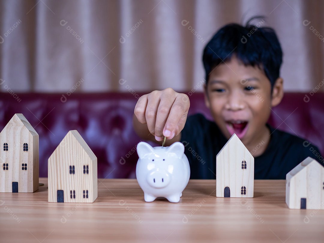 Menino economizando dinheiro em um cofrinho de porco branco. Conceito de economia. Poupar para o futuro.