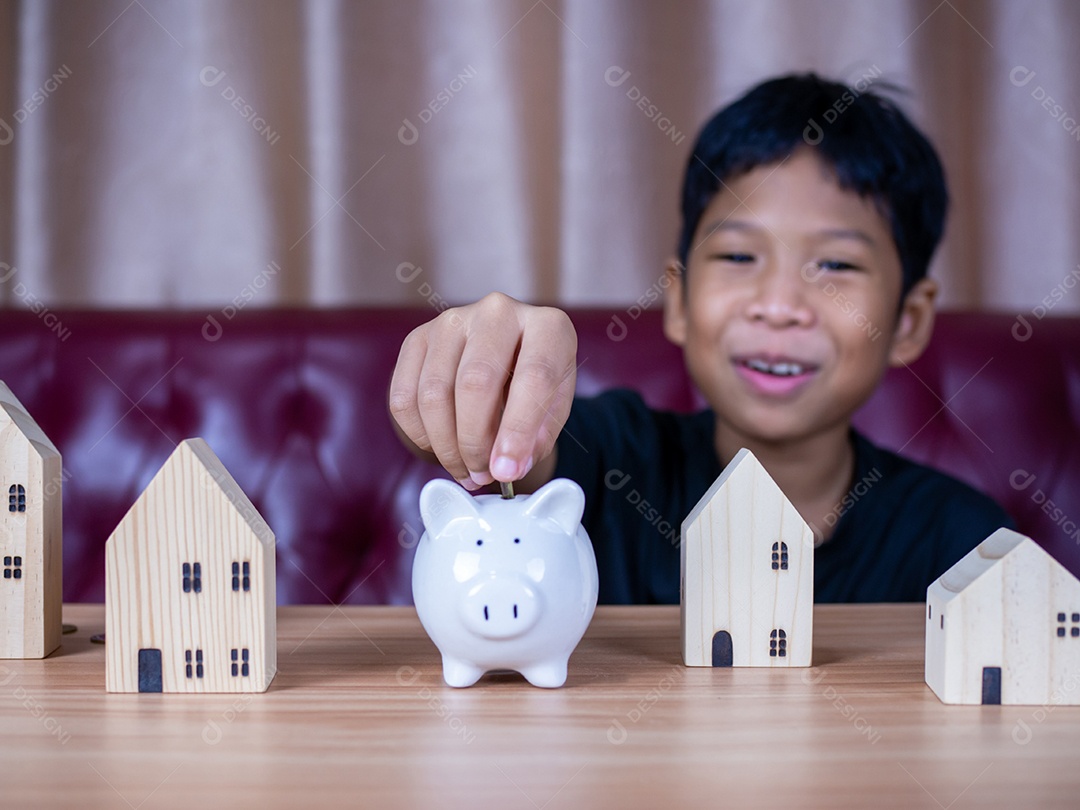 Menino economizando dinheiro em um cofrinho de porco branco. Conceito de economia. Poupar para o futuro.