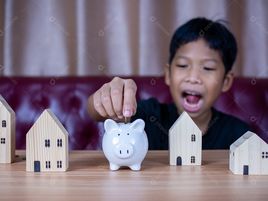 Menino economizando dinheiro em um cofrinho de porco branco. Conceito de economia. Poupar para o futuro.