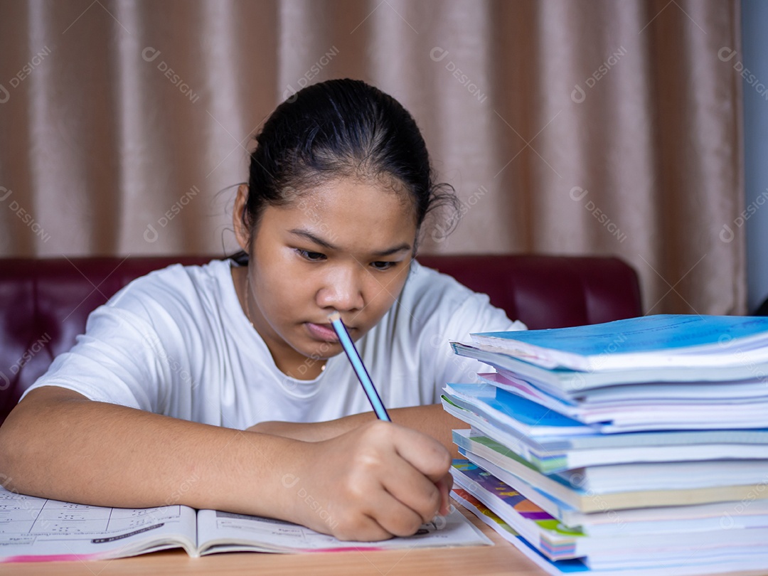 Girl doing homework on a wooden table and there was a pile.