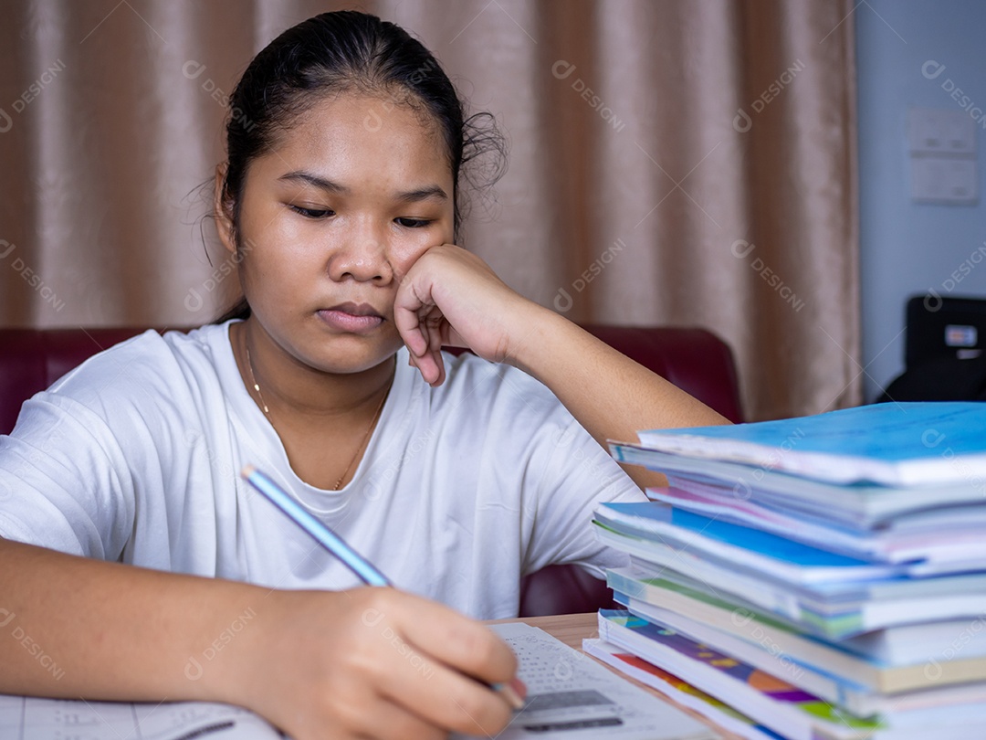 Menina fazendo lição de casa em uma mesa de madeira e havia uma pilha.