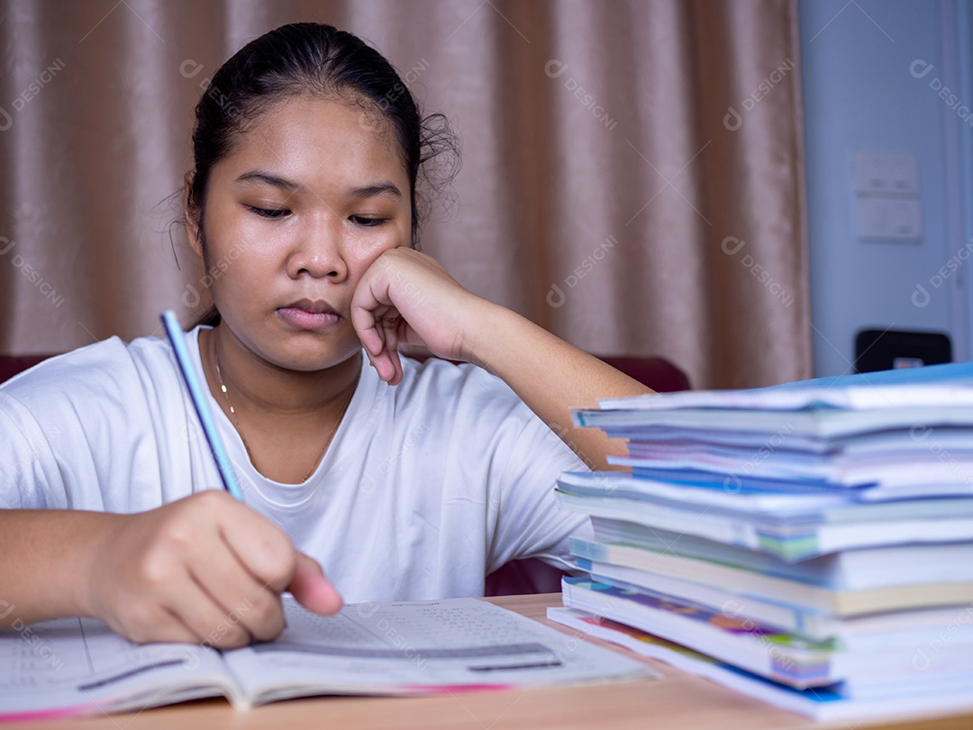 Menina fazendo lição de casa em uma mesa de madeira e havia uma pilha.