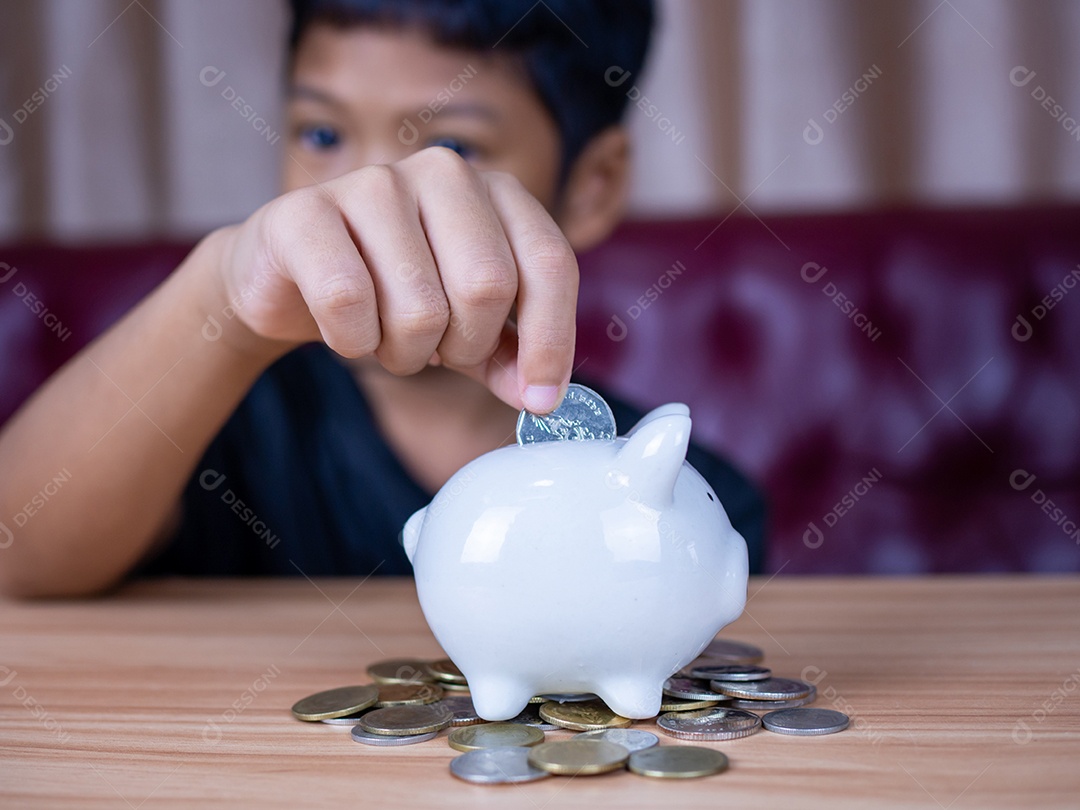 Menino economizando dinheiro em um cofrinho de porco branco. Conceito de economia. Poupar para o futuro.