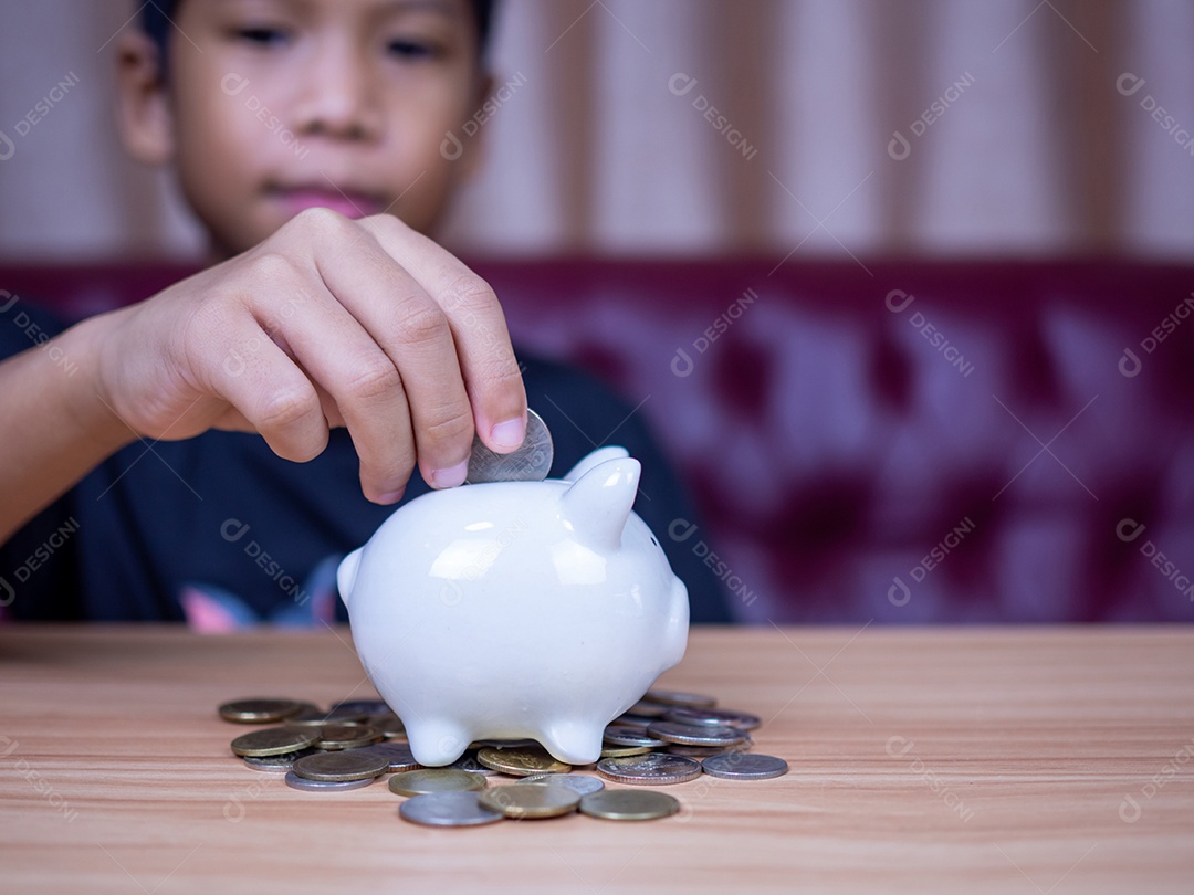Menino economizando dinheiro em um cofrinho de porco branco. Conceito de economia. Poupar para o futuro.