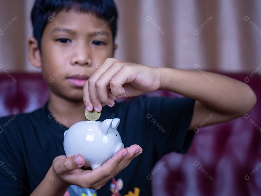 Menino economizando dinheiro em um cofrinho de porco branco. Conceito de economia. Poupar para o futuro.