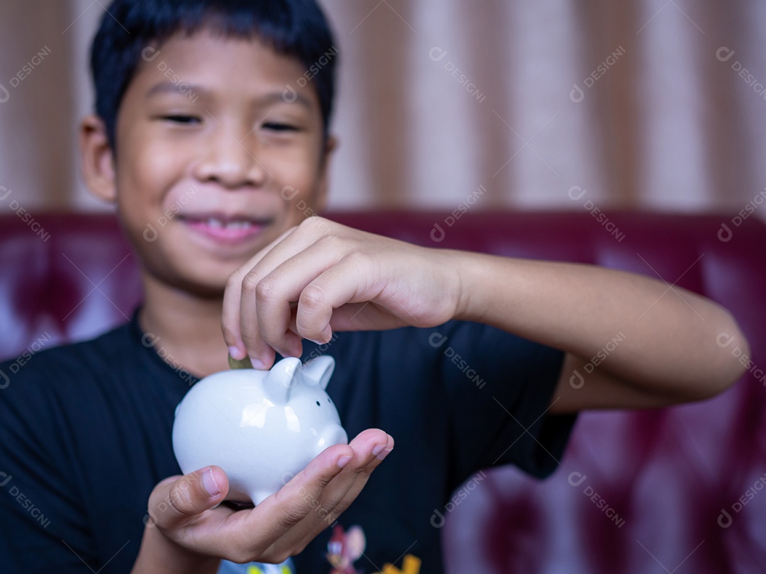 Menino economizando dinheiro em um cofrinho de porco branco. Conceito de economia.