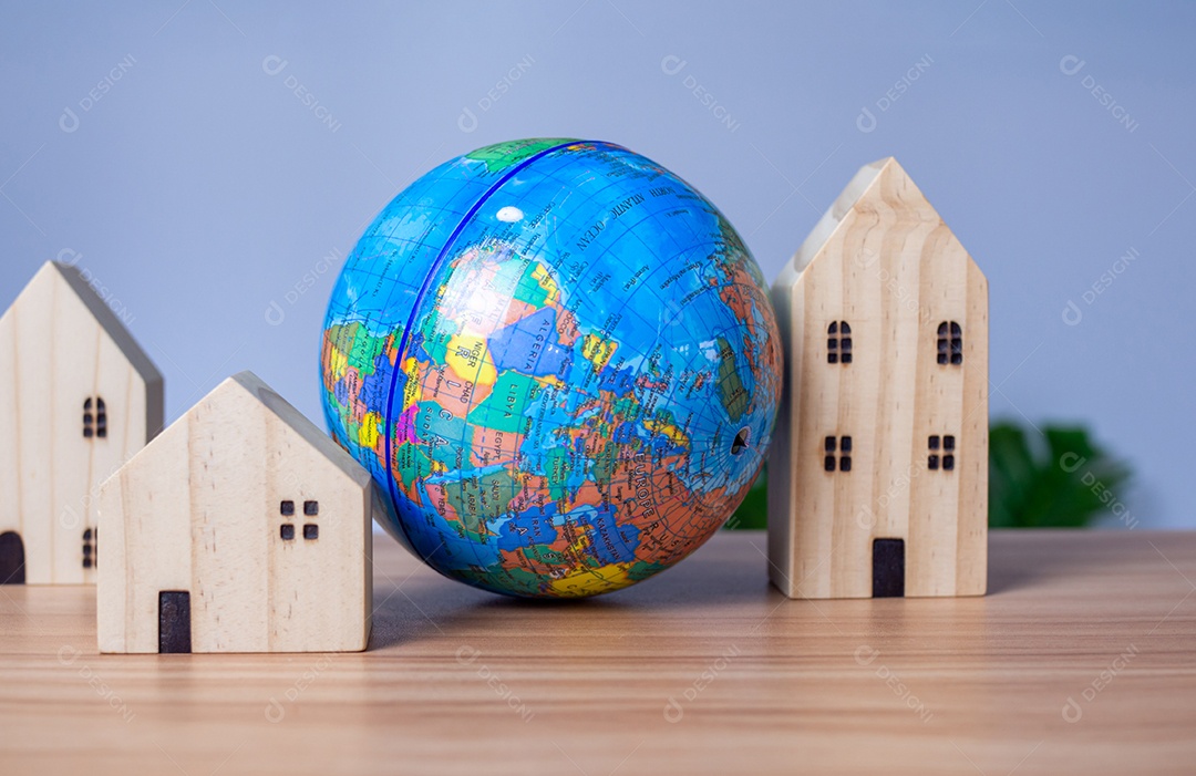 A wooden model house is placed next to a replica globe.