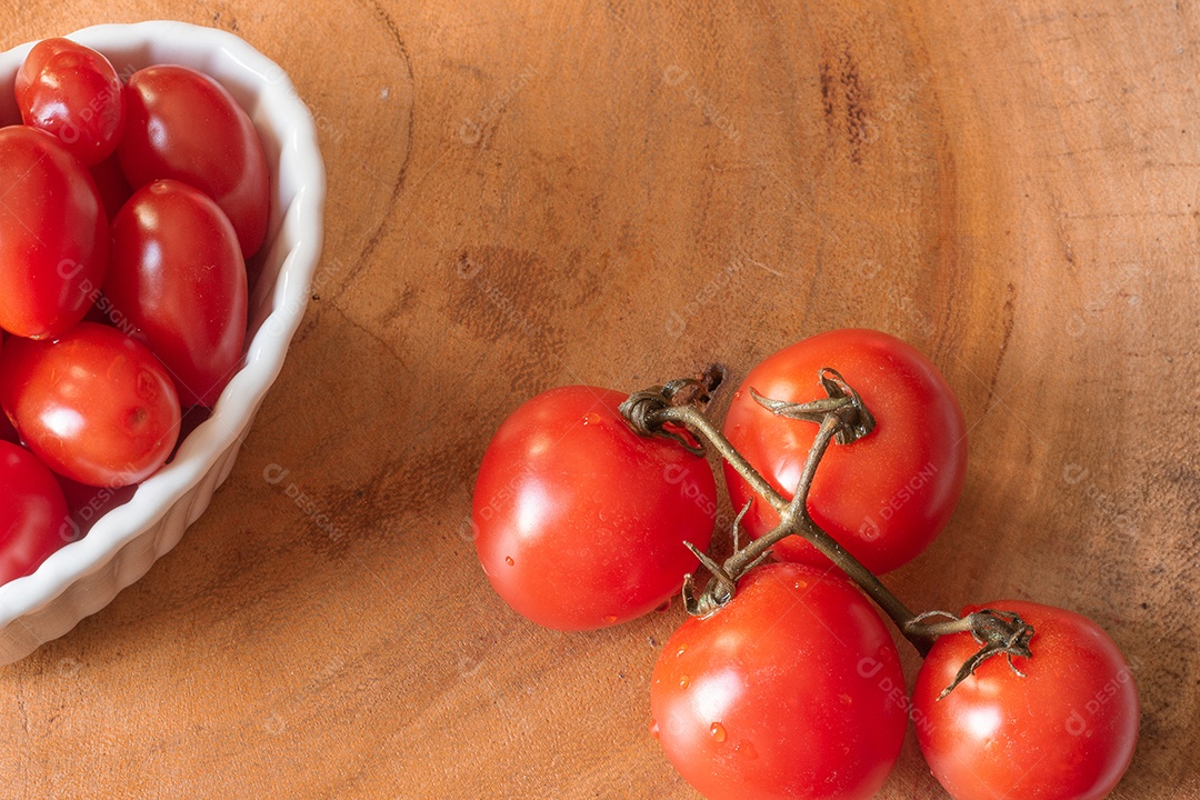 vários tomates pequenos dentro de uma tigela branca em uma mesa de madeira