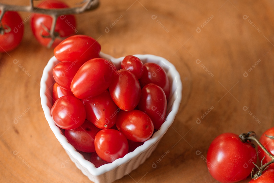 vários tomates pequenos dentro de uma tigela branca em uma mesa de madeira