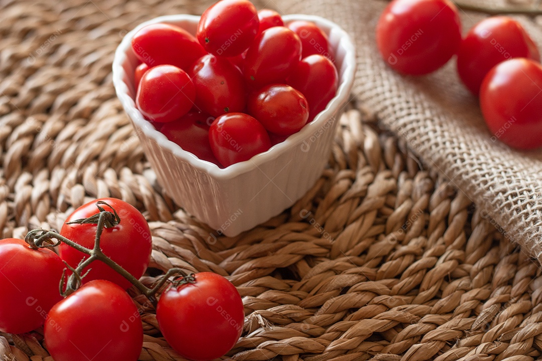 tomates dentro de uma tigela branca e sobre uma mesa de palha