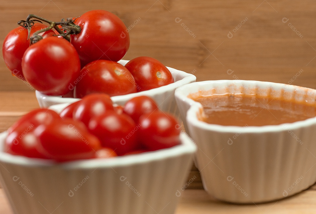 vários tomates pequenos dentro de três tigelas em uma mesa de madeira